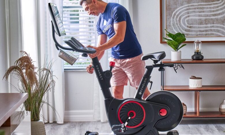 Person adjusts the height of an Echelon Connect stationary bike in their home gym.