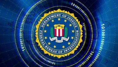 Close-up of the Federal Bureau of Investigation (FBI) seal, encircled by binary code, on a dark blue background.