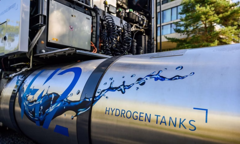 Close-up of a hydrogen fuel tank on a truck, featuring a stylized water design and the words 'Hydrogen Tanks'.