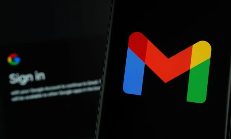 Close-up of Gmail app on smartphone, with blurred Gmail login page in background.
