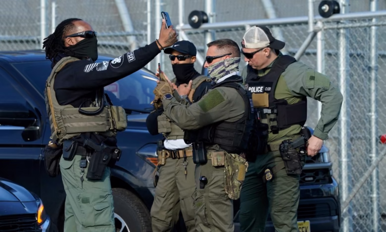 Law enforcement officers in tactical gear use cell phones, possibly documenting a scene.