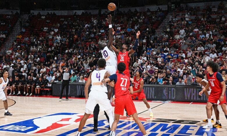 Intense basketball action at an NBA Summer League game. Players jump for the ball, surrounded by a cheering crowd.