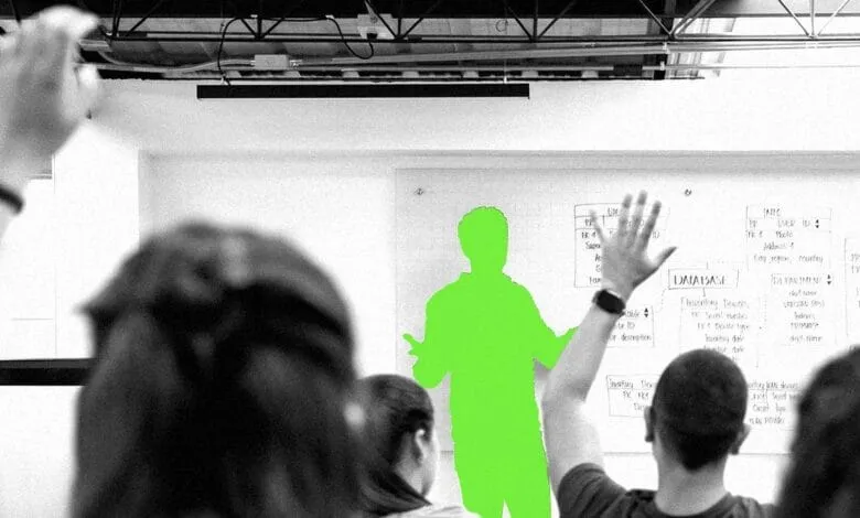 Presenter in lime green gives a presentation to a grayscale audience with hands raised, whiteboard shows database design.