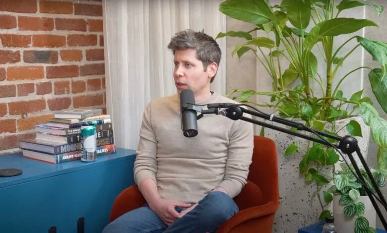 Sam Altman, CEO of OpenAI, sits in a chair during a podcast interview, speaking into a microphone.