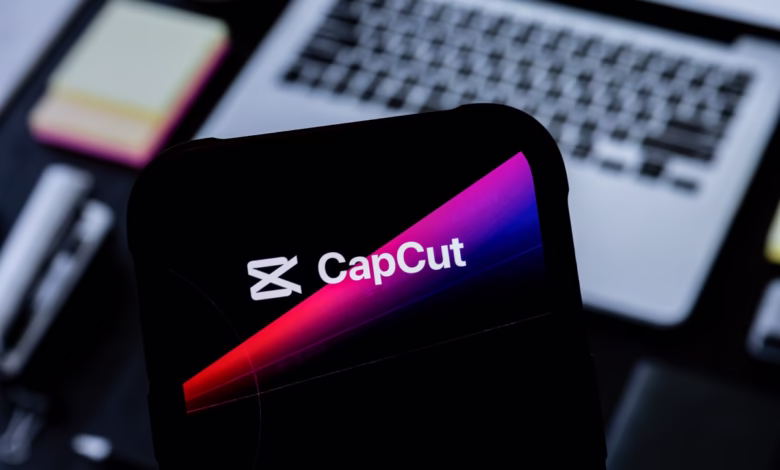 Close-up of a smartphone displaying the CapCut app logo, a stylized 'X' and the word 'CapCut' in white against a gradient pink and blue background.