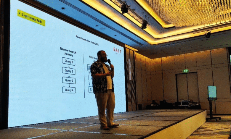 Speaker presents at SALT Search conference, a diagram of a 'Narrow Search Journey' is displayed on a large screen behind them.