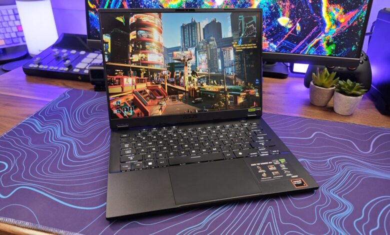 Asus TUF Gaming laptop displaying a vibrant cityscape game scene on a purple desk mat.