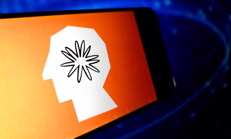 Close-up of a smartphone displaying the BetterUp app logo: a stylized white head with a black flower inside, set against an orange background.