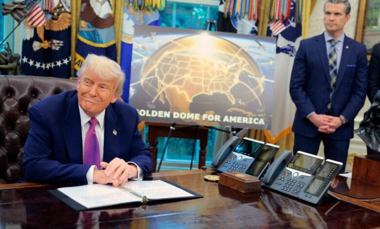 President Donald Trump sits at his desk in the Oval Office, reviewing documents. A man stands behind him.
