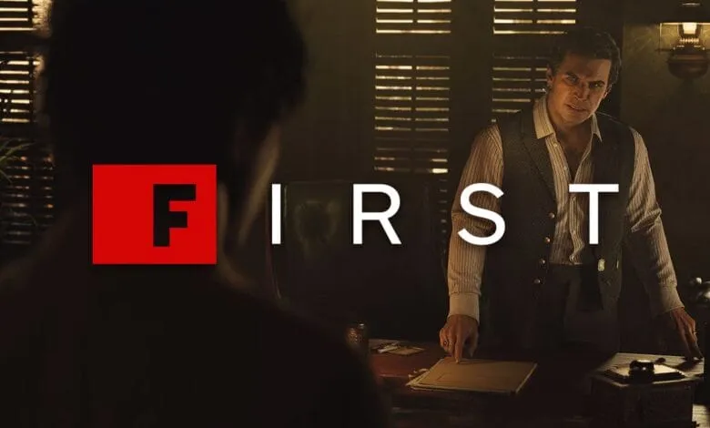 Man in vest sits at desk, intense expression, 'FIRST' overlaid. Dark, suspenseful mood.