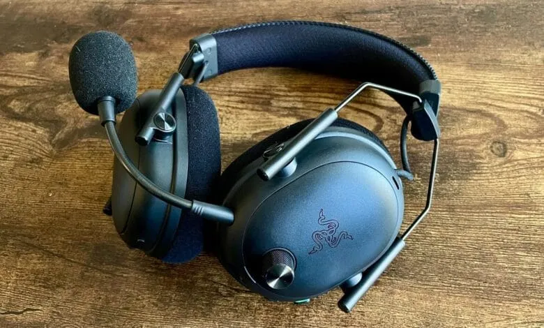 Razer BlackShark V2 Pro gaming headset rests on a dark wood surface. The headset is black with a microphone attached.