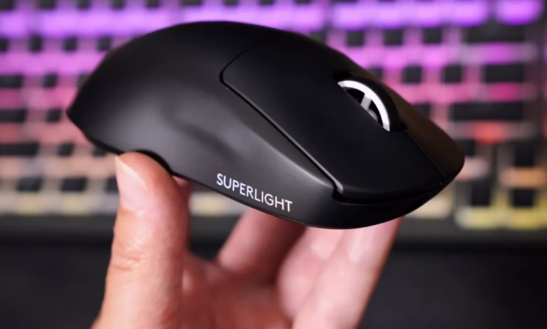 Close-up of a hand holding a black Logitech G Pro X Superlight 2 gaming mouse. The mouse is sleek and features a white 'SUPERLIGHT' logo.