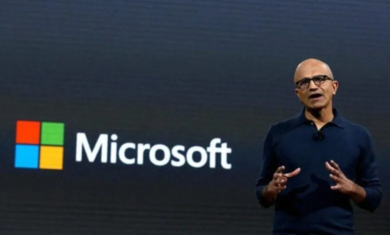Satya Nadella, Microsoft CEO, speaks at a presentation with the Microsoft logo in the background.