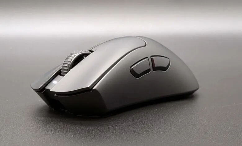 A sleek, black computer mouse with a textured scroll wheel and two additional buttons sits on a dark gray surface.