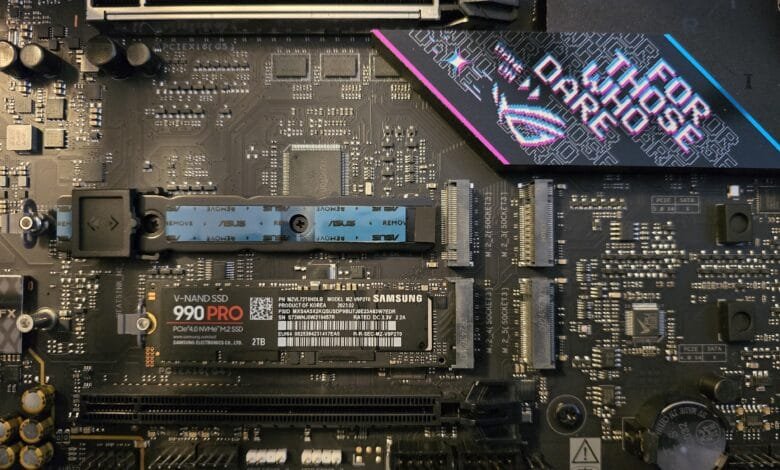 Close-up of a computer motherboard with a Samsung 990 Pro 2TB NVMe SSD installed. The motherboard features an ASUS ROG Strix branding.