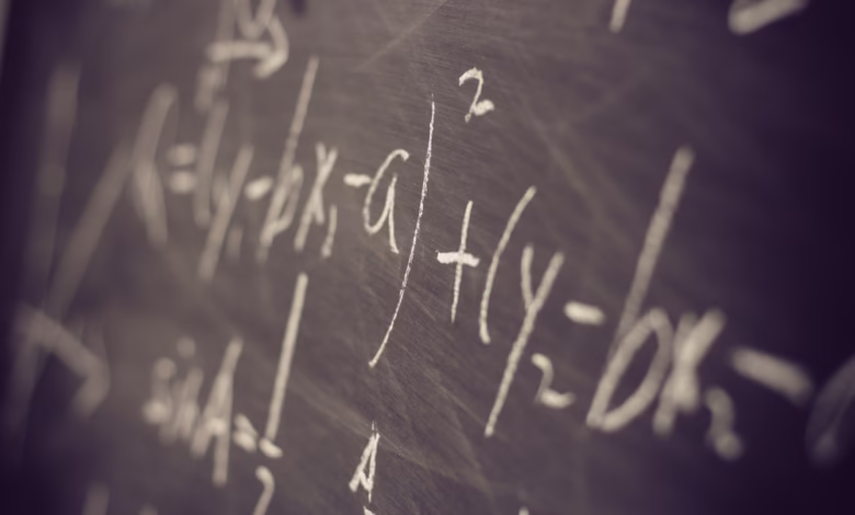 Close-up of a chalkboard filled with complex mathematical equations written in white chalk.