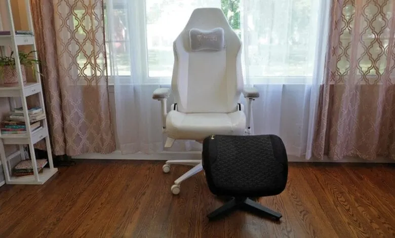 White Secretlab gaming chair with gray headrest and black footrest sits in front of a window with sheer curtains.