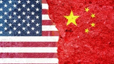 US and Chinese flags painted on a cracked wall, symbolizing strained relations.