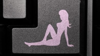 Close-up of a keyboard key featuring a pale pink female silhouette reclining. The key is dark gray.