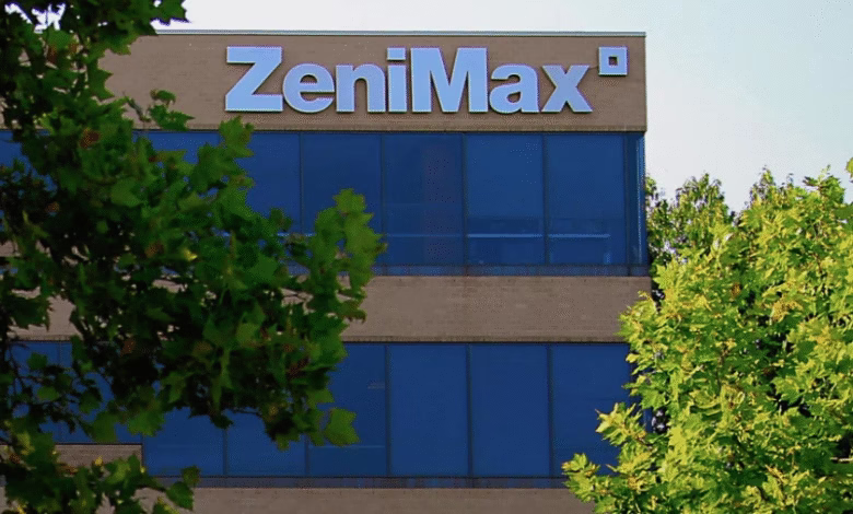 The Zenimax building, partially obscured by trees, displays its name in large white letters on a tan building with blue windows.
