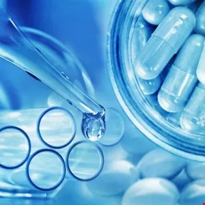 Close-up of blue pills and liquid dripping from a pipette into test tubes, suggesting pharmaceutical research.