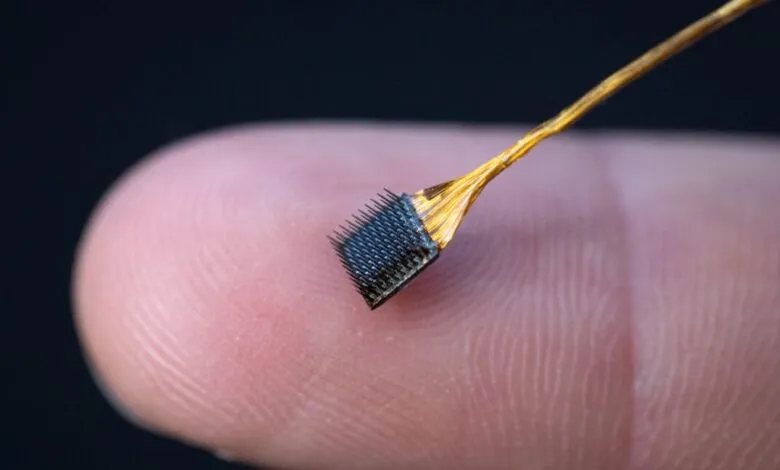 Close-up of a tiny microelectrode array held on a fingertip, used for brain research at Stanford.