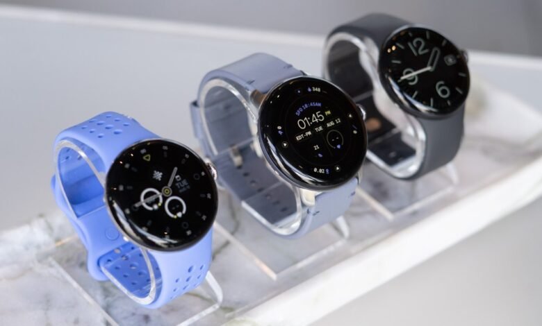 Three modern smartwatches displayed on stands, featuring blue, gray, and black bands.