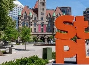 Large orange 'Saint Paul' letters in a plaza with a historic building in the background.