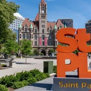 Large orange 'Saint Paul' letters in a plaza with a historic building in the background.