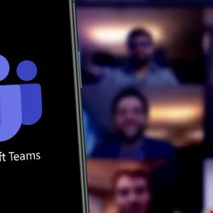 Microsoft Teams app on a smartphone screen, showing a video conference with blurred participants in the background.