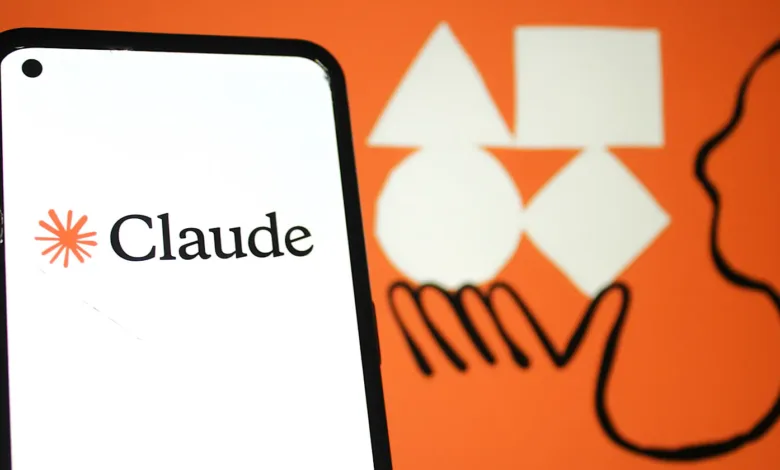 Close-up of a smartphone displaying the Claude AI logo against a vibrant orange background with abstract shapes.