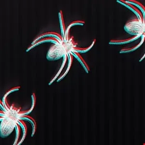 Three plastic spiders with a 3D effect against a dark background.