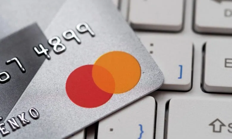 Close-up of a Mastercard resting on a laptop keyboard, showcasing the card's design and partially visible numbers.