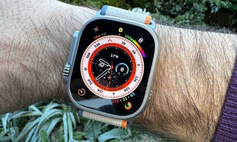 Close-up of a person's wrist wearing a titanium Apple Watch Ultra with a beige band, displaying a compass and altitude.