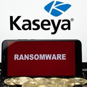 Smartphone displaying 'Ransomware' on a red screen in front of the Kaseya logo, with cryptocurrency coins below.