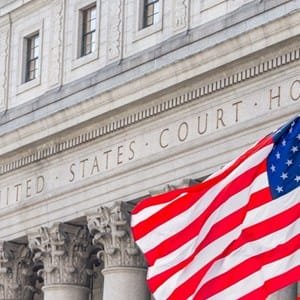 US flag waving in front of a United States Court House building.
