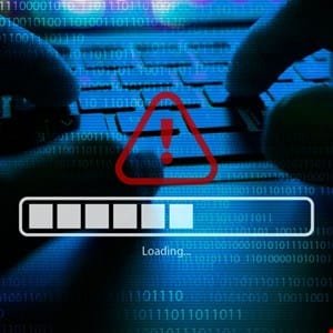 Close-up of hands typing on a keyboard with a red warning triangle and 'Loading...' progress bar on screen.