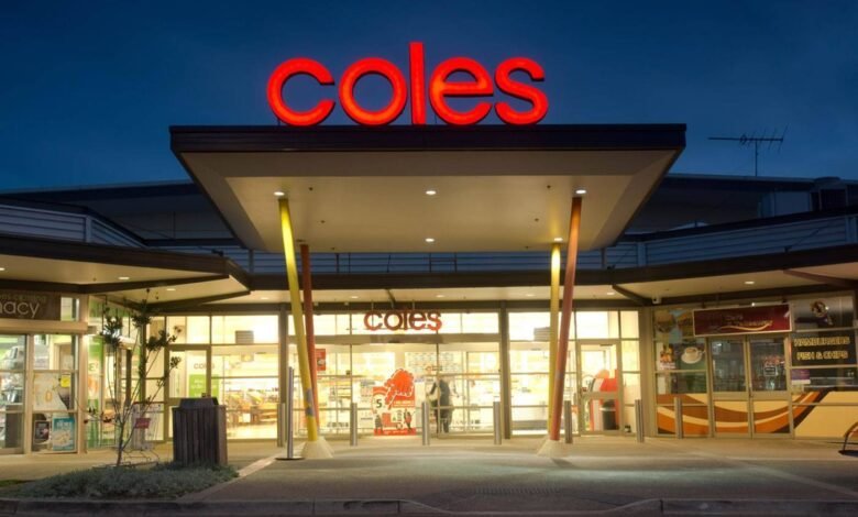 Illuminated Coles supermarket entrance at night. Red Coles signage is prominent.