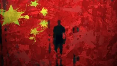 Silhouette of a person against a stylized Chinese flag backdrop with paint splatters.