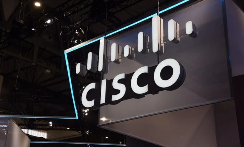 Close-up of a Cisco logo hanging from the ceiling, illuminated with bright white lettering and a blue outline.