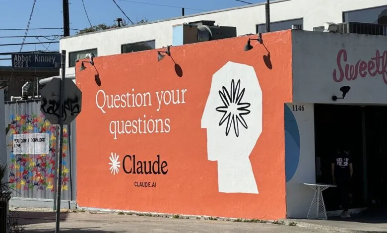 Large orange mural featuring Claude.ai logo and the phrase 'Question your questions'.