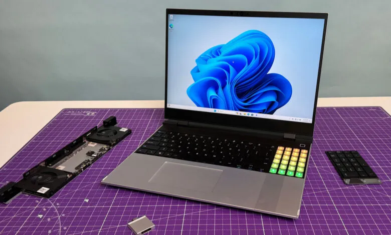 Laptop with Windows 11, disassembled parts, and a separate number pad on a purple cutting mat.