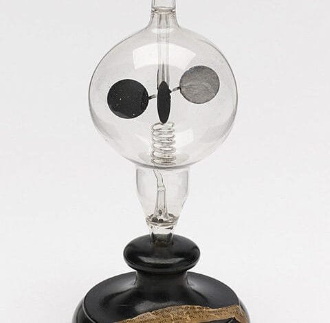 Antique glass radiometer with a black base and a rotating vane inside a clear bulb.