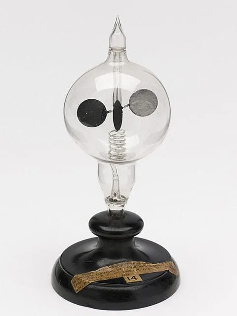 Antique glass radiometer with a black base and a rotating vane inside a clear bulb.