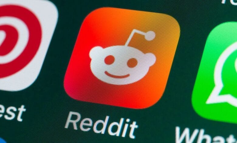Close-up of a smartphone screen displaying the Reddit app icon among other social media apps.