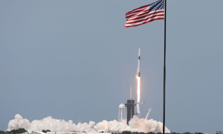 SpaceX Falcon 9 rocket launching, with an American flag waving in the background.