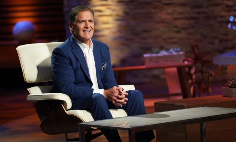 Mark Cuban, Shark Tank investor, sits smiling in a white leather chair.