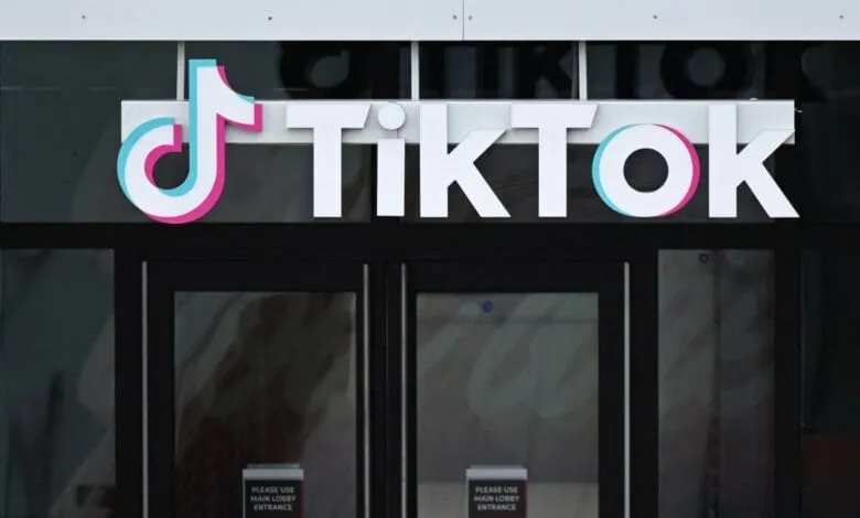 TikTok logo displayed prominently on a building's exterior, above a set of dark glass doors.
