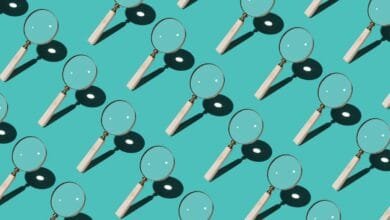 Repeating pattern of magnifying glasses with light wood handles against a teal background.