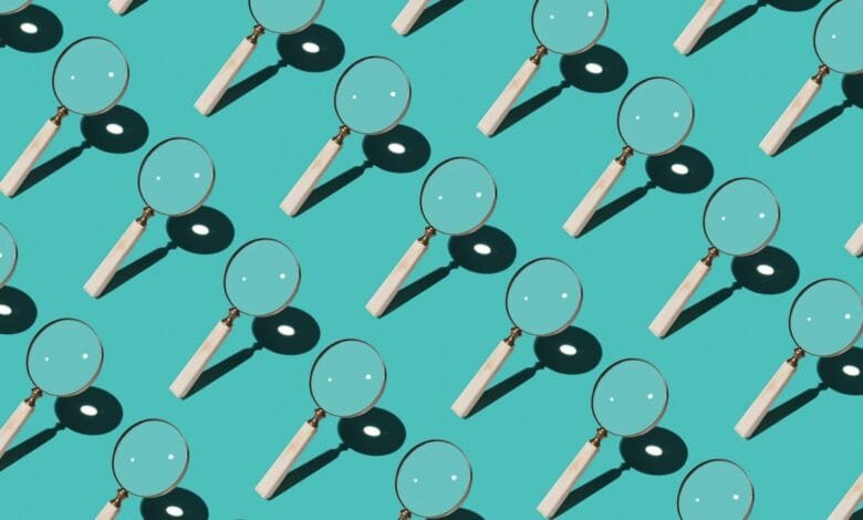 Repeating pattern of magnifying glasses with light wood handles against a teal background.